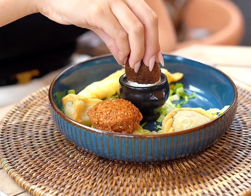 Aperçu de la maquette Soleil : falafel trempé dans la sauce, sur la table du Byblos